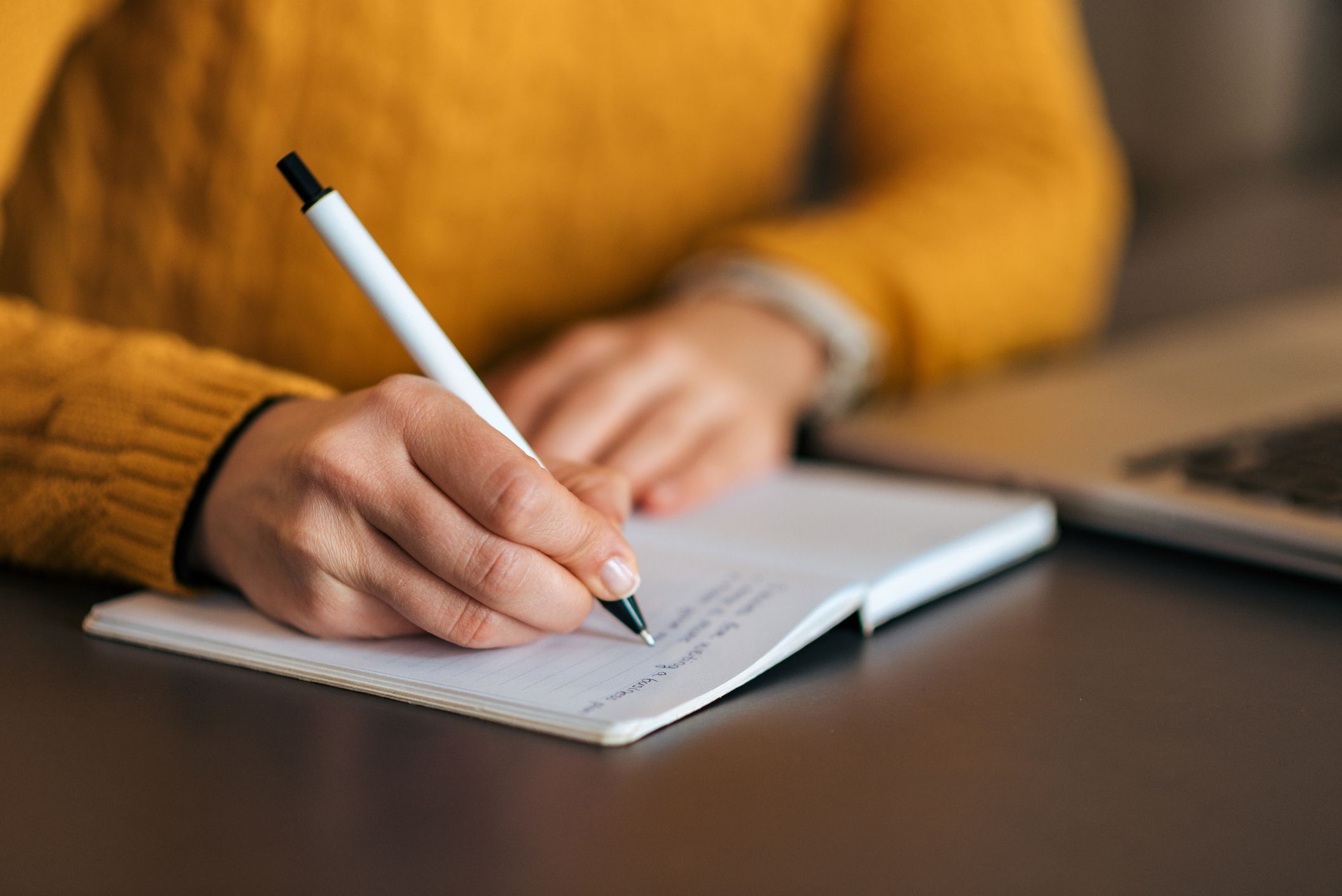 Young female musician writing her music biography in a notebook.