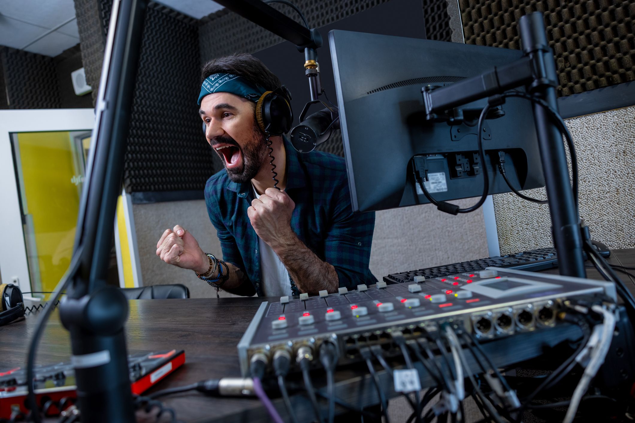 Young male radio presenter appears happy about the new music he is playing on the radio.