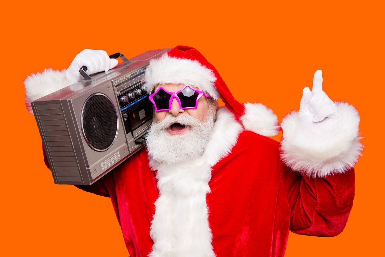 Santa Clause wearing pink star-shaped sunglasses and listening to music on a boom box.