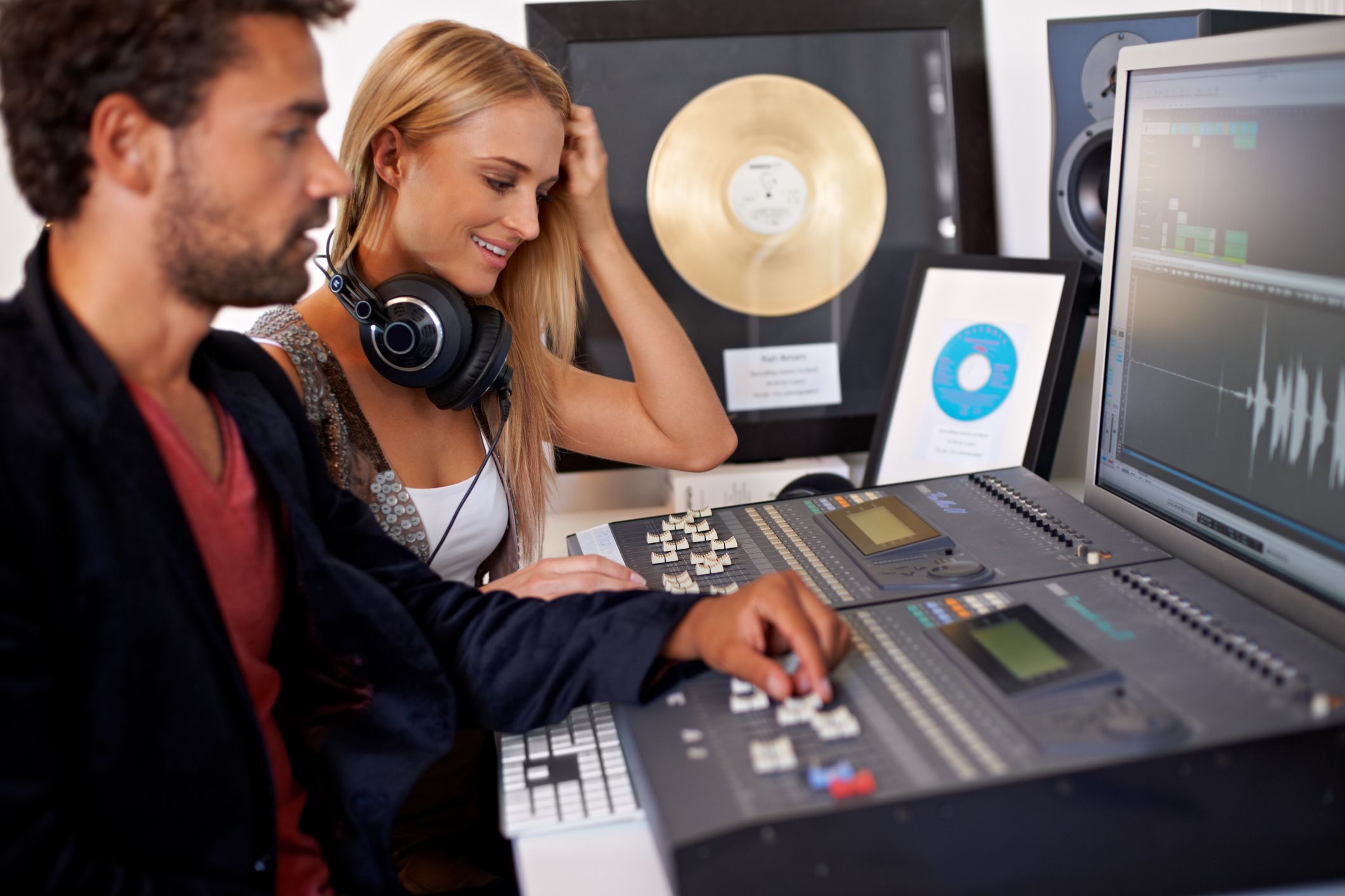 Male and female sat in a studio producing music with a gold disc displayed in the background